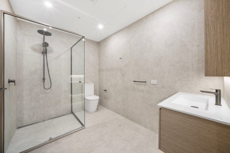 Bathroom with frameless glass shower, stone-look tiles and timber vanity in a LaCurva apartment