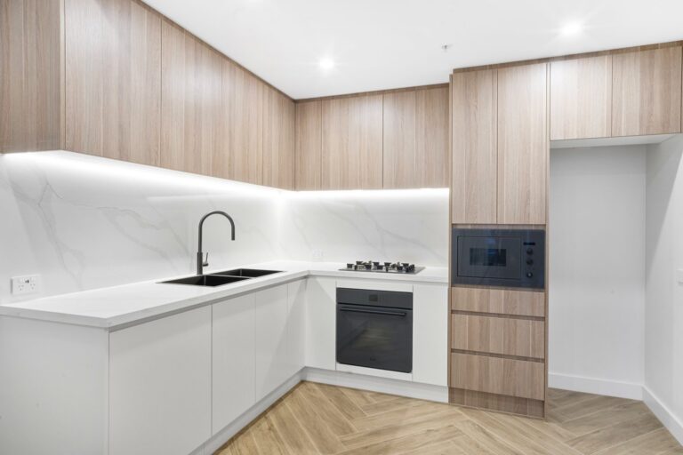 Kitchen with timber-look cabinetry, marble-look splashback and herringbone floor in a LaCurva apartment