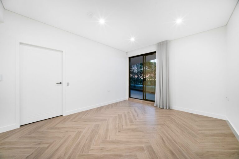 Open living area with herringbone timber-look floor and sliding doors to the balcony in a LaCurva apartment